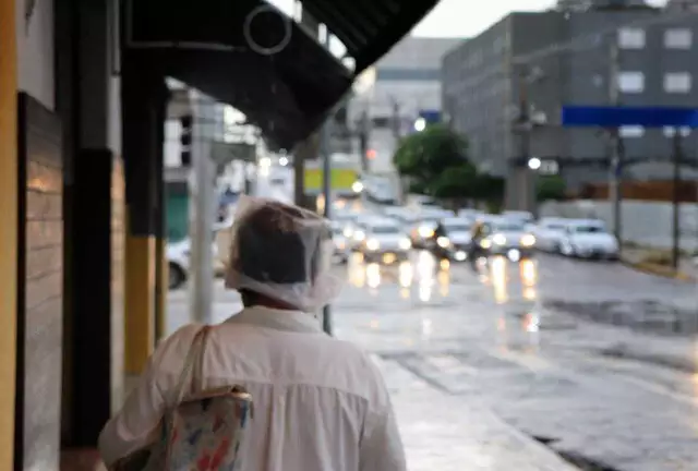 Pedestre anda pela Avenida Calógeras com sacola plástica na cabeça para se proteger da chuva (Foto: Osmar Veiga)... veja mais em https://www.campograndenews.com.br/meio-ambiente/defesa-civil-alerta-para-temporal-em-campo-grande