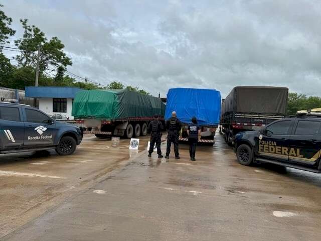 Policiais da PF e Receita Federal ao lado dos caminhões carregados com toneladas de acetato de etila apreendidas na fronteira em Corumbá (Foto: Divulgação / Polícia Federal)